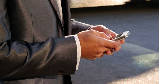 Mid section of businessman using mobile phone on street