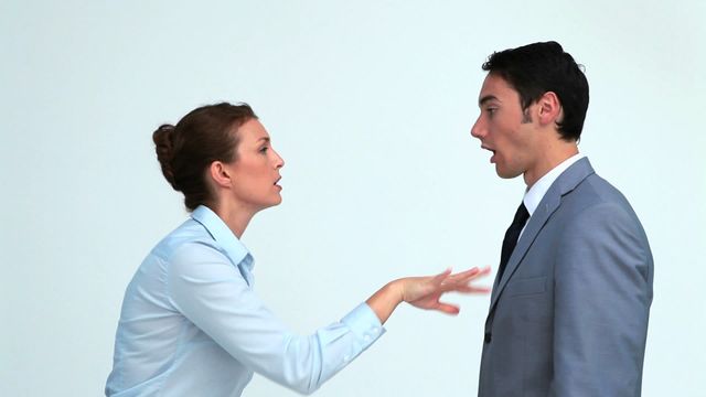 Within a controlled studio environment, a businesswoman is engaged in conversation with a businessman, both of whom appear involved in a tense or heated discussion. This image is suitable for use in contexts related to workplace communication, conflict resolution, or negotiation strategies.