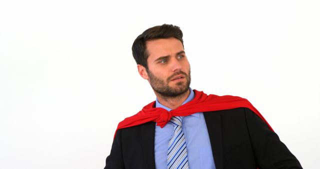 A young Caucasian man dressed in business attire with a red superhero cape looks off to the side, with copy space. His expression and costume suggest a concept of empowerment or work-life balance challenges.