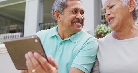 Smiling Senior Couple Enjoying Technology Outdoors