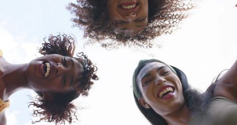 Laughing african american women leaning in together outdoors looking down