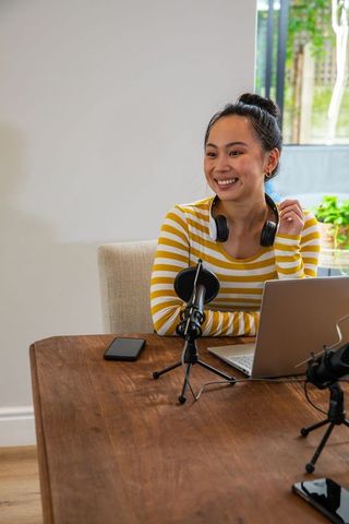 Asian Woman Hosting Podcast with Equipment in Bright Home Studio