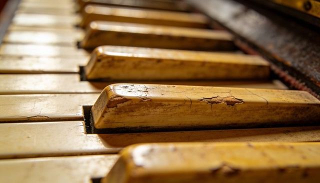Weathered piano keys showing cracked ivory patina and chipped lacquer vintage acoustic piano