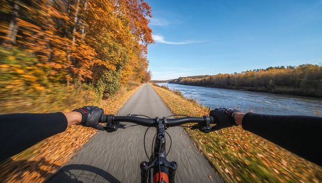 Cyclist Riding Along Scenic Autumn Trail by River