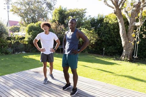 Diverse male friends enjoying workout with fitness trackers in backyard