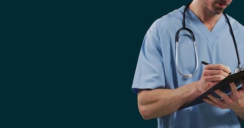 Male doctor in scrubs writing on clipboard for healthcare