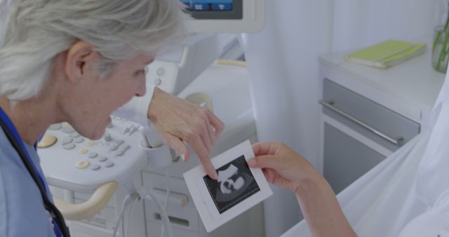 Caucasian woman reviews an ultrasound image, with copy space. In a medical office, the sonographer analyzes the fetal development.