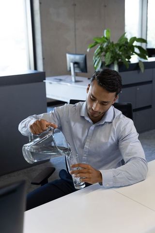 Professional Man Pouring Water in Office Environment