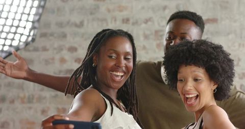 African american friends laughing and taking selfie in bright loft studio