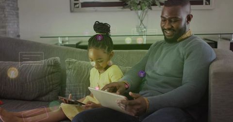 Father and daughter bonding on couch using tablets with floating chat icons for learning