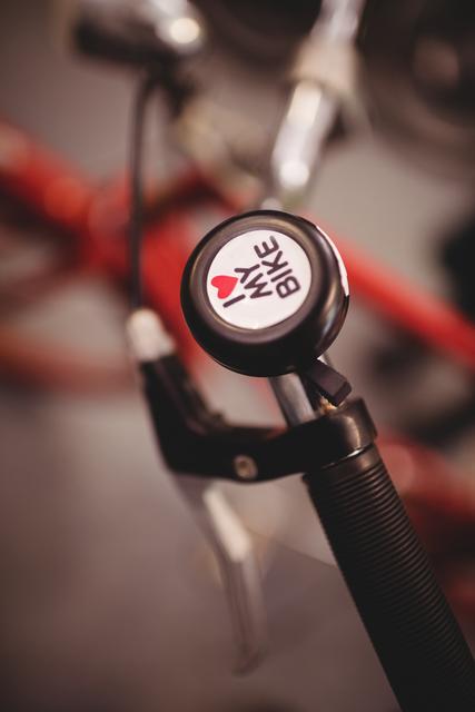 Close-up of a bicycle bell on a handlebar in a workshop. Ideal for use in articles or advertisements related to cycling, bike maintenance, and biking accessories. Perfect for promoting cycling gear, bike repair services, or hobbyist cycling communities.