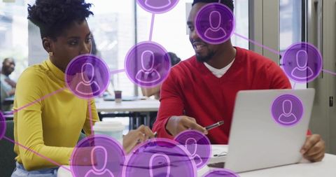 Collaborating and reviewing laptop and documents with purple network overlay in coworking space