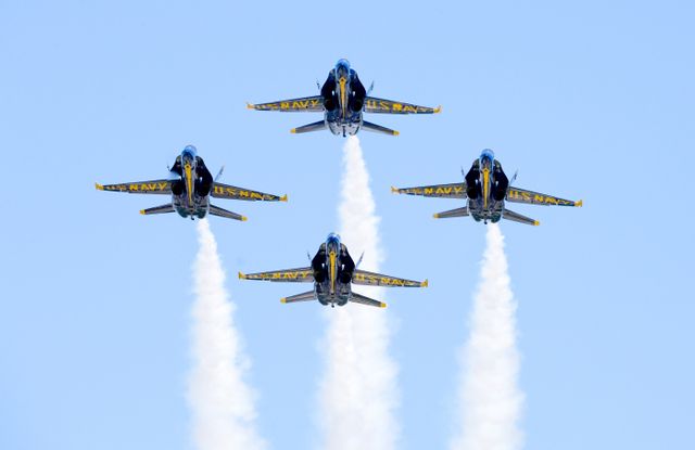 This image shows the US Navy Blue Angels performing formation aerobatics against a clear sky. Ideal for use in content related to air shows, military aviation, aviation safety, and aviation enthusiasts. This visually striking scene can attract attention for educational materials, articles on military precision and training, recruitment ads, or event promotions.