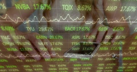 Hands tapping tablet and typing laptop with green stock tickers and analytics overlay