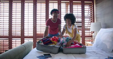 Couple Packing Bags Before Trip in Sunny Bedroom Setting