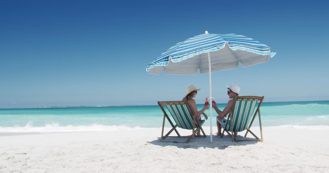 Couple Relaxing Under Beach Umbrella by Ocean - Download Free Stock Images Pikwizard.com
