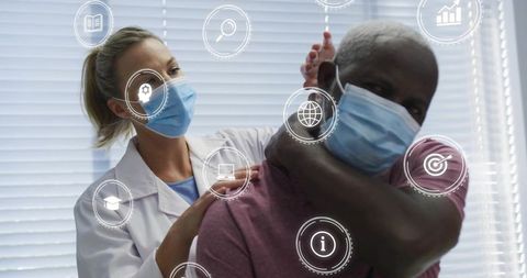 Clinician performing neck and shoulder assessment on masked patient with telehealth data icons