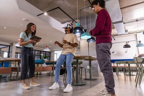 Young Diverse Coworkers Testing VR Headset and Collaborating in Modern Coworking Lounge