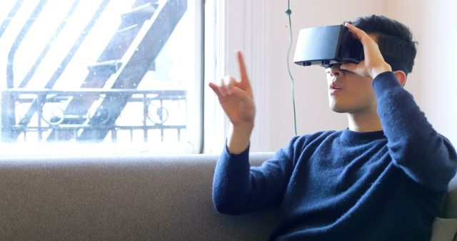 An Asian man gestures immersed in a VR experience, possibly gaming or learning. - Download Free Stock Photos Pikwizard.com