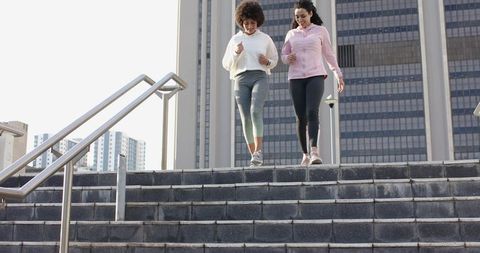 Diverse friends walking down urban stairs in athletic wear exercising together