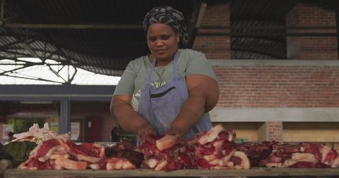 Woman butcher handling fresh meat in market stall