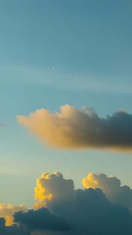 Vertical sunset cloudscape lighting golden-hour cumulus while tiny moon drifting