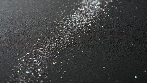 Iridescent Glitter Trail Sparkling on Dark Surface with Pastel Bokeh and Macro Texture