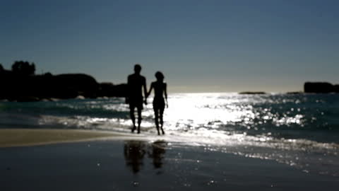 Couple Walking on Moonlit Beach Creating Romantic Silhouette