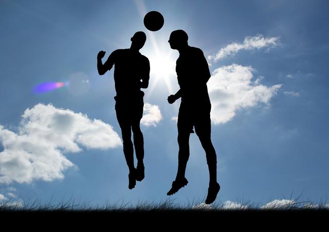 Two silhouetted soccer players are jumping to head a ball against a bright sky with clouds. This dynamic and energetic scene is perfect for illustrating concepts of teamwork, competition, and athleticism. Ideal for use in sports-related content, motivational posters, and advertisements promoting outdoor activities and team sports.