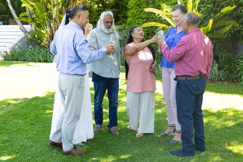 Bride toasting with multigenerational guests at backyard garden wedding celebration