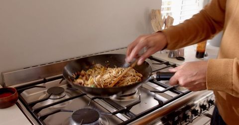home chef cooking stir-fry noodles on gas stove - Download Free Stock Images Pikwizard.com