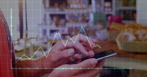Hands holding smartphone at shop counter with financial chart overlay for retail analytics