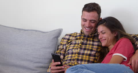 Couple Relaxing on Sofa with Smartphone at Home