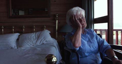 Elderly Woman in Wheelchair Looking Thoughtful by Window