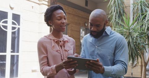 Colleagues Collaborating with Digital Devices in Courtyard