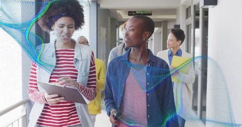 Walking Diverse Team Collaborating with Tablet and Documents in Modern Office Hallway