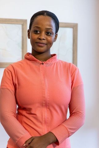 African american woman posing in coral zip jacket, calm minimalist portrait for lifestyle use