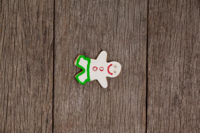Overhead view of a gingerbread man cookie on a rustic wooden surface. Perfect for holiday-themed designs, Christmas cards, festive recipes, or seasonal advertisements.
