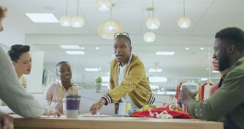 Studio team collaborating around table with textiles while designer presenting ideas