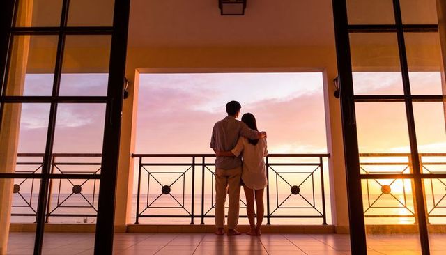 Romantic couple embracing on ocean balcony at sunset over calm seascape horizon