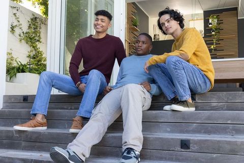 Multiethnic teenage friends sitting and chatting on modern steps casual outdoor hangout