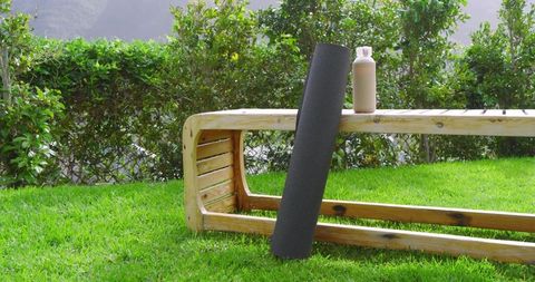Yoga mat and eco bottle near garden bench inspiring outdoor wellness