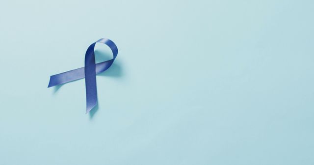Purple ribbon symbolizing cancer awareness placed on light blue background. This can be used for healthcare campaigns, disease prevention, support groups, charity events, and awareness materials.