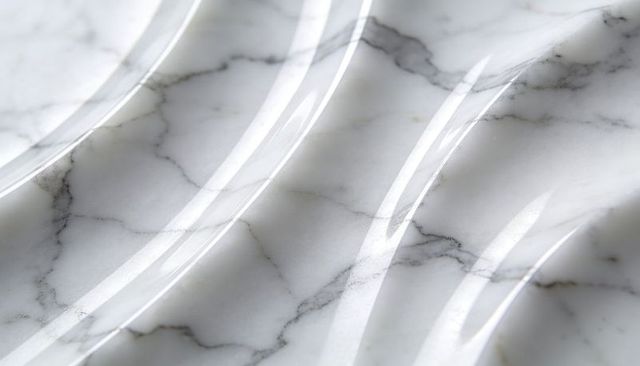 Polished white marble slab reflecting studio light with wavy ridges and gray veins