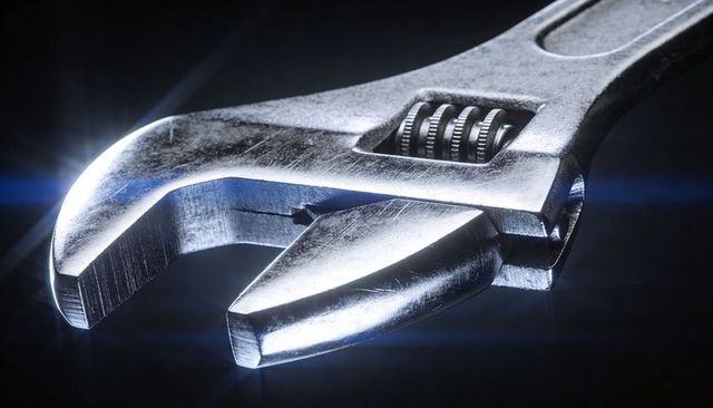 Chrome crescent wrench macro showing jaw and worm screw under dramatic studio light closeup scratche