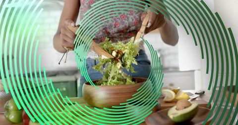 Home cook tossing fresh salad in bright modern kitchen