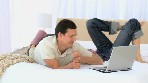 Couple Relaxing on Bed While Enjoying Laptop Entertainment