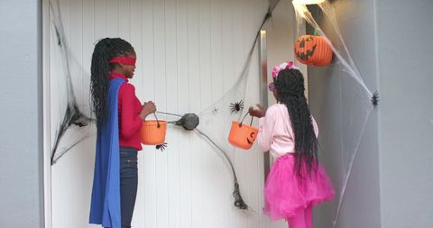 African american girls trick or treating in superhero cape and pink tutu halloween