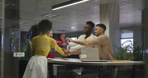 Placing hands together for teamwork at high table in modern glass office