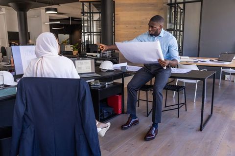 Collaborative Diverse Architects Reviewing Blueprint in Modern Office